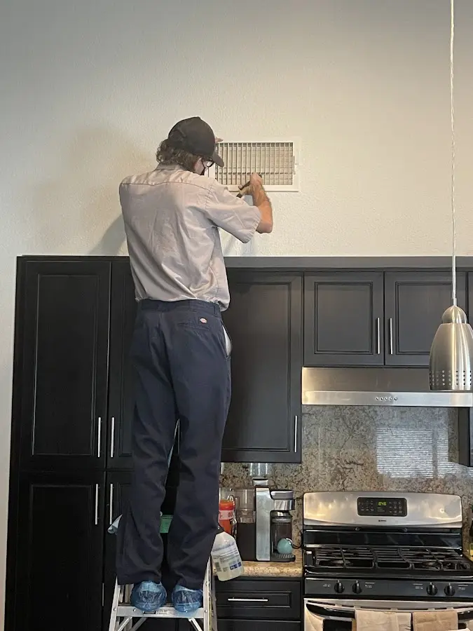 Technician inspecting an air vent during HVAC service in St. Martinville